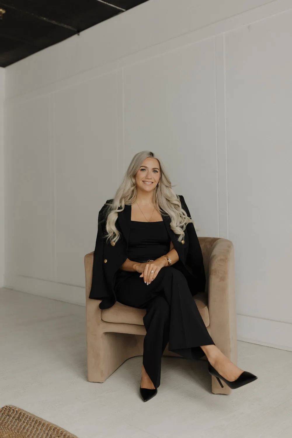 Marissa Lubera seated in a white-paneled studio
