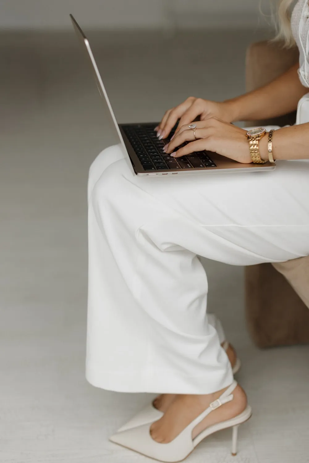 Marissa Lubera working on a laptop, dressed in ivory